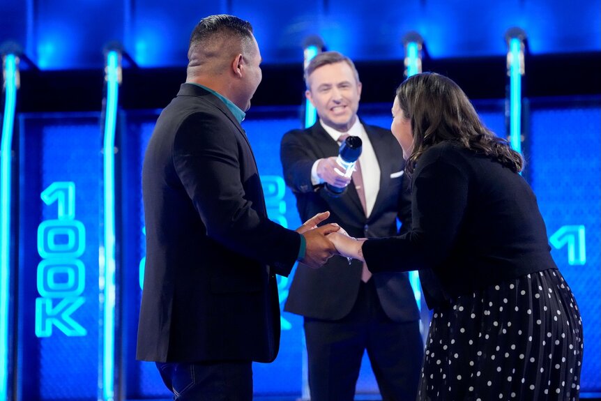 Chris Hardwick holds a mic up to contestants on The Wall Episode 602.