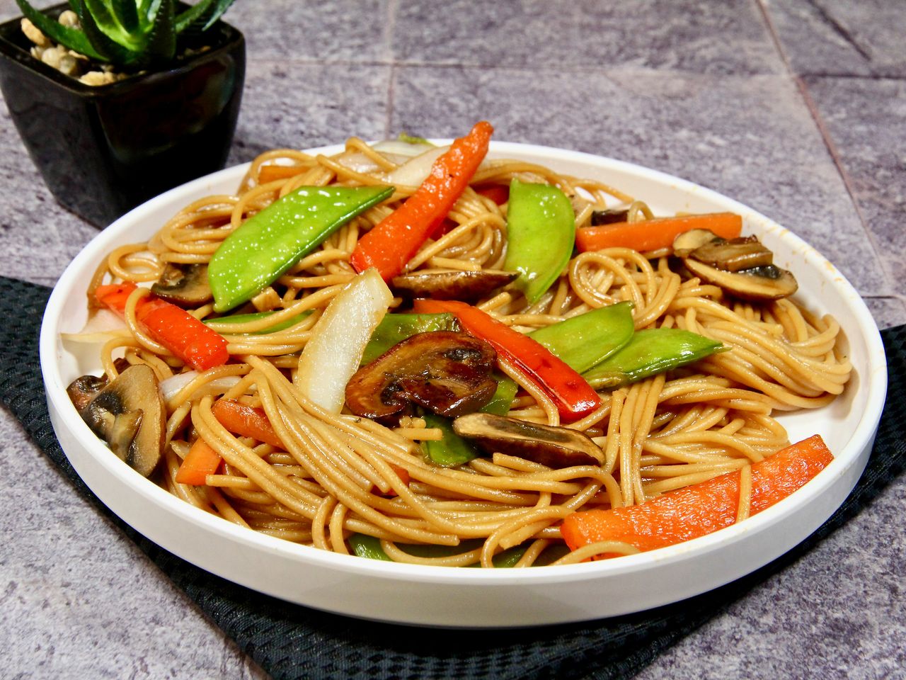 white bowl of noodle bowl with veggies and mushrooms photographed outdoors