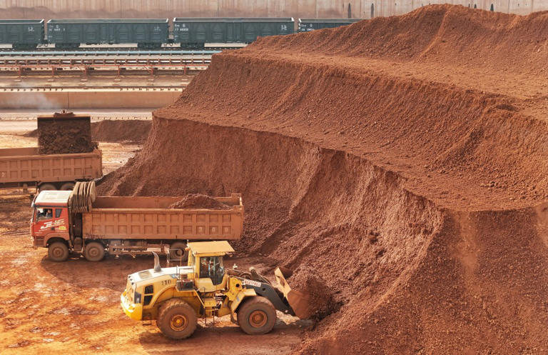 Heavy machinery handling bauxite ore is seen at the Yantai port in eastern China’s Shandong province on October 29, 2025.