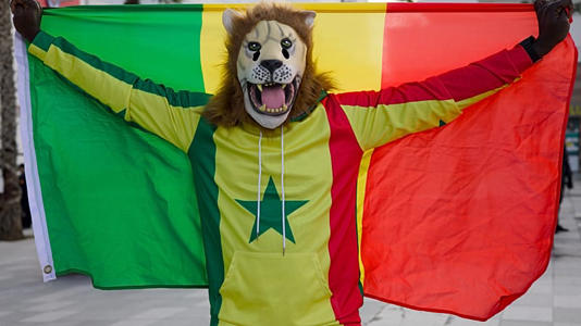 Pape, un supporter sénégalais déguisé en lion, brandit le drapeau du Sénégal lors de la Coupe d'Afrique des nations à Tanger, au Maroc, le 23 décembre 2025.
