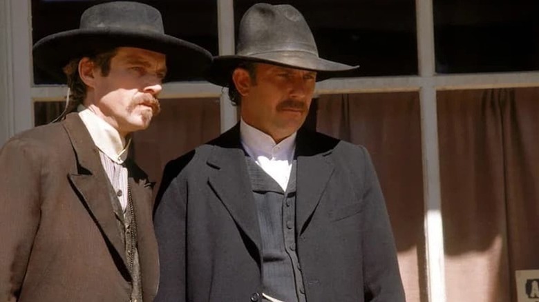Doc Holliday (Dennis Quaid) and Wyatt Earp (Kevin Costner) stare intently at something together in Wyatt Earp