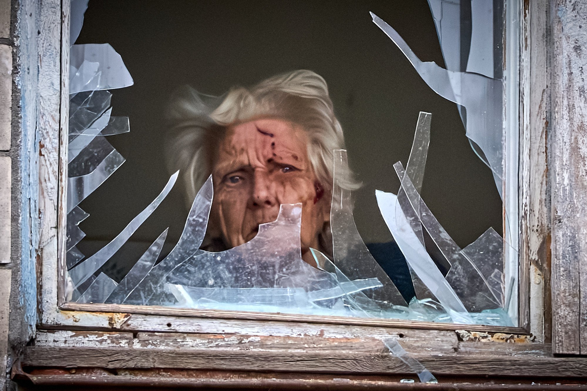 An injured elderly woman looks out of her broken window as an apartment building was hit by a Russian drone during an aerial attack in Kyiv, Ukraine, on December 23, 2025. Photo: AP