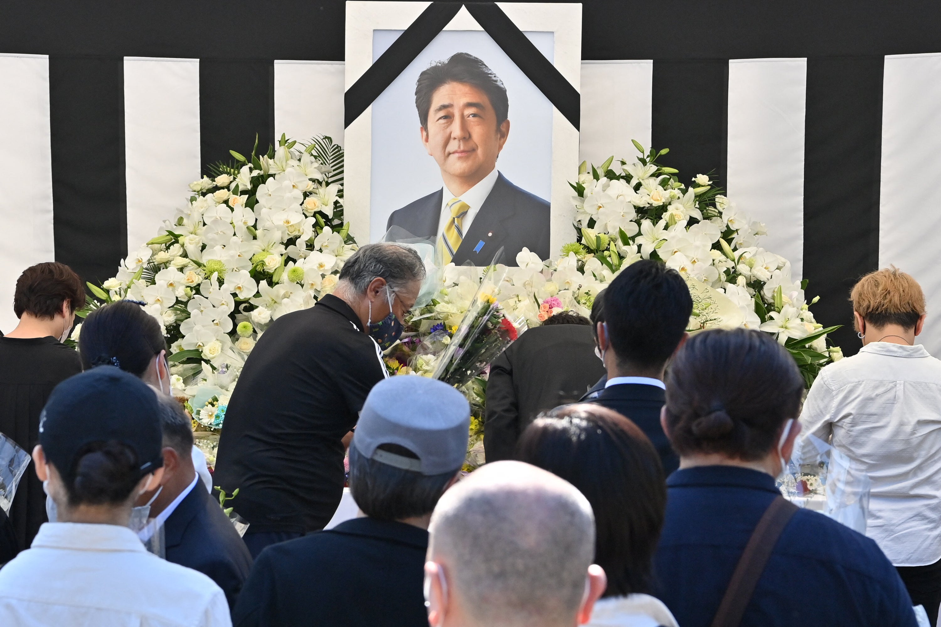 This photo taken on 27 September 2022 shows people offering their respects to former Japanese prime minister Shinzo Abe outside the Nippon Budokan in Tokyo, ahead of his state funeral later in the day (AFP via Getty Images)