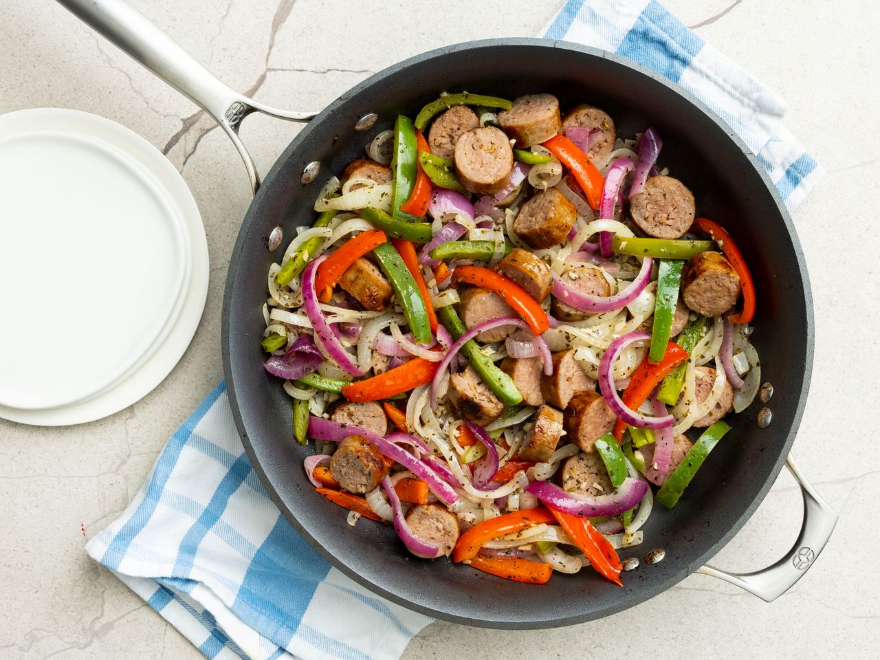 overhead view looking into a skillet of Italian sausage, peppers and onions