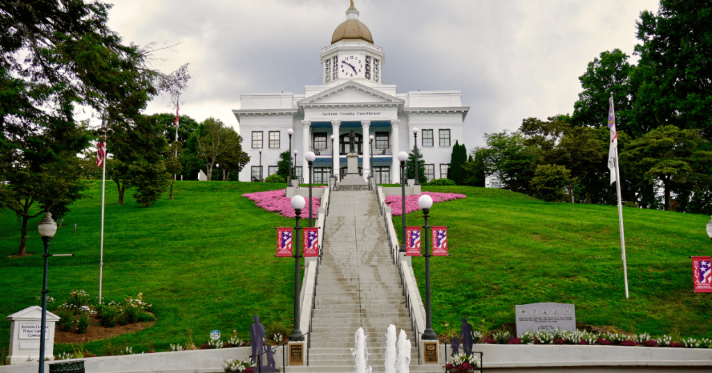 The white exterior of the Jackson County Courthouse on a hill overlooking the main street of Sylva.