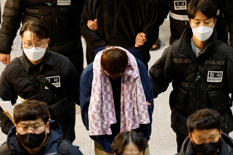 Police officers escort South Koreans allegedly involved in scam operations in Cambodia after being forcibly repatriated from Cambodia, at Incheon International Airport in Incheon, South Korea January 23, 2026. REUTERS/Kim Soo-hyeon