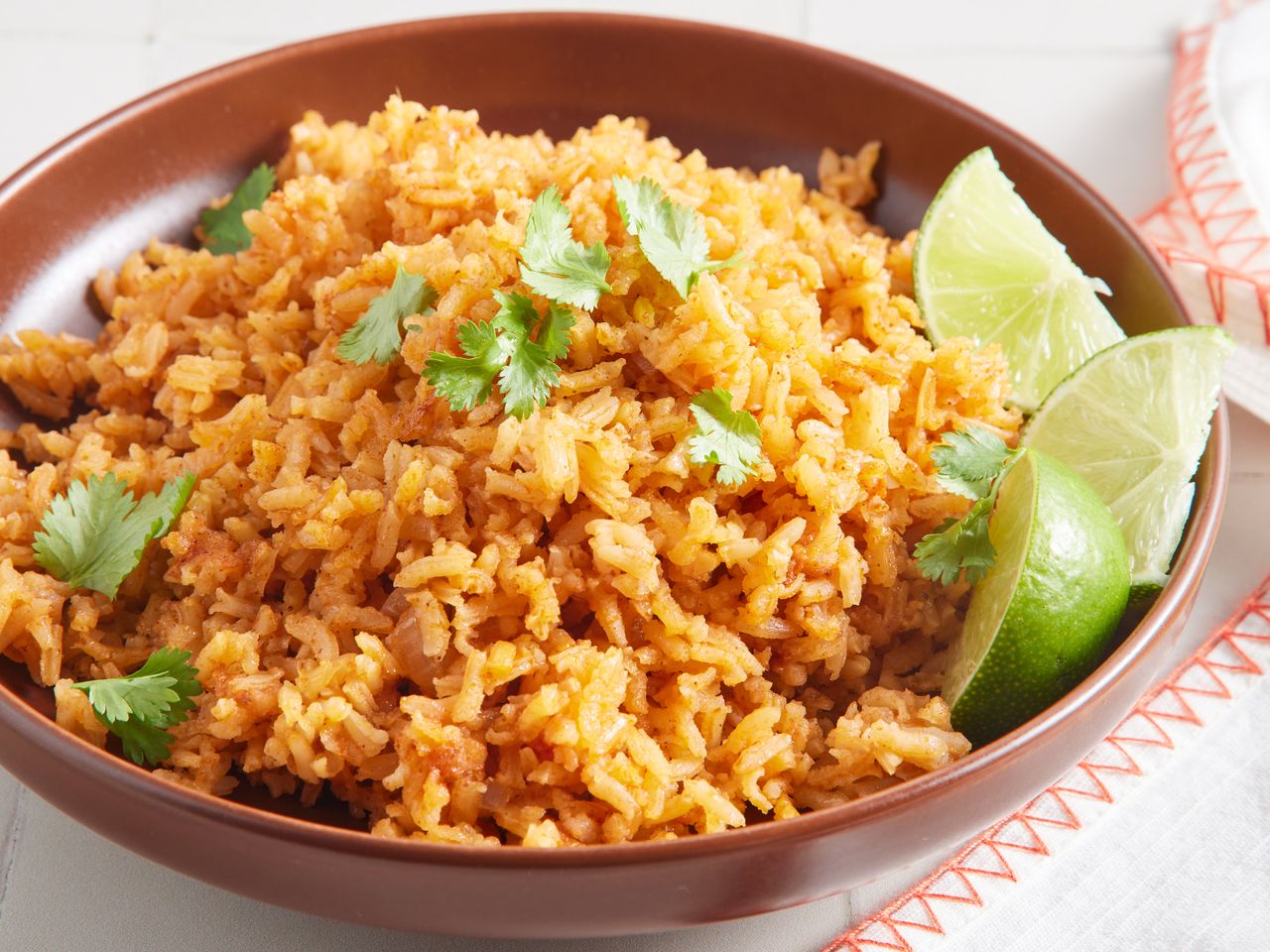 A bowl of Mexican rice topped with fresh cilantro and served with lime wedges