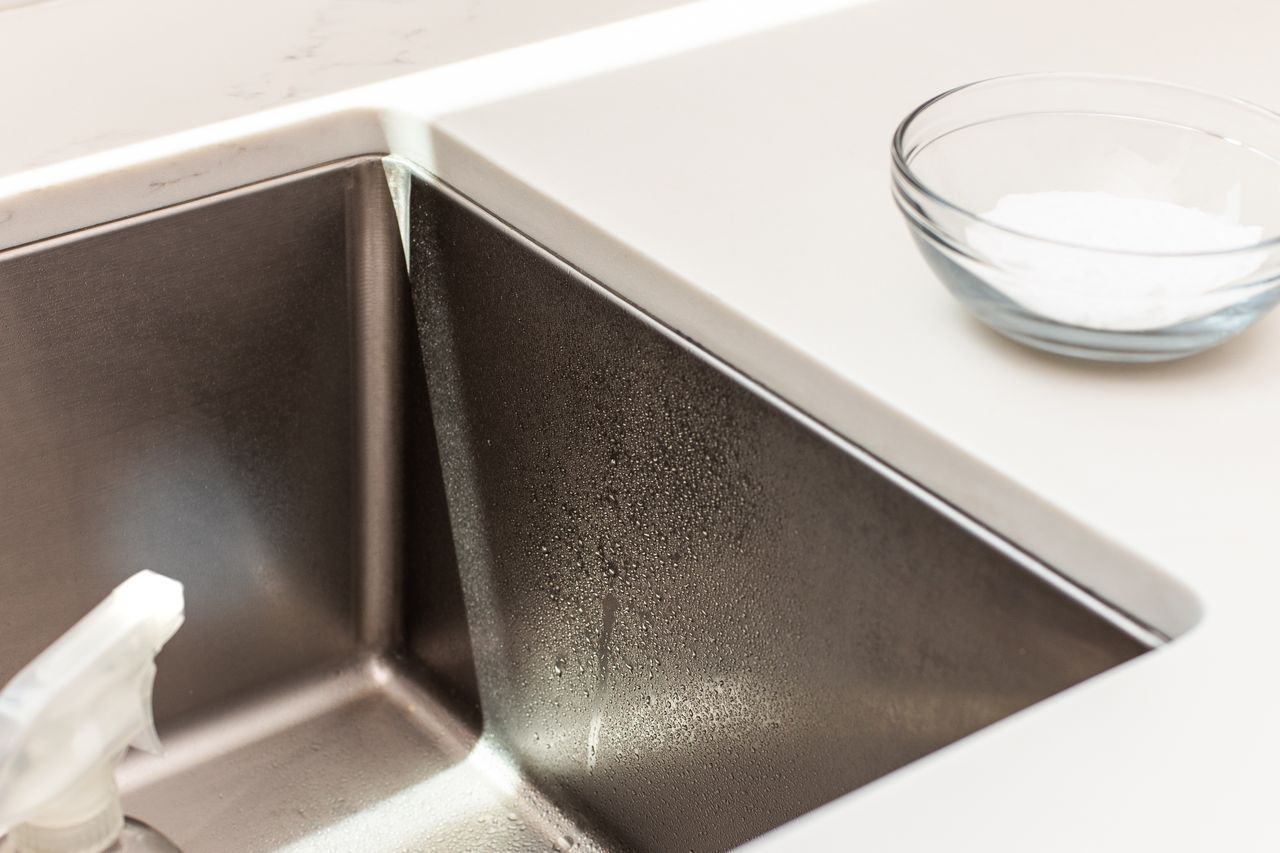 Distilled white vinegar sprayed on stainless steel sink to but through mineral deposits