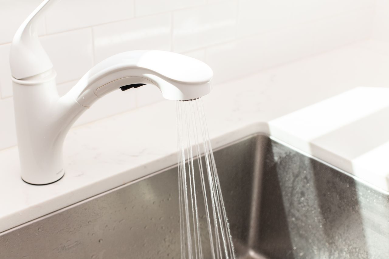 Kitchen sink running water over stainless steel sink