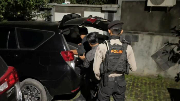 BAWA KOPER - Dikawal polisi, tim penyidik KPK memasukkan barang bukti hasil operasi penggeledahan mereka ke mobil, Sabtu malam (24/1/2026).