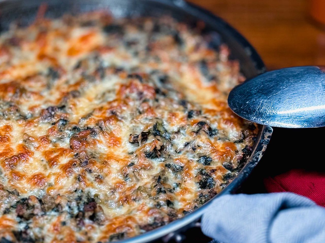 ground beef spinach casserole topped with cheese in round casserole dish