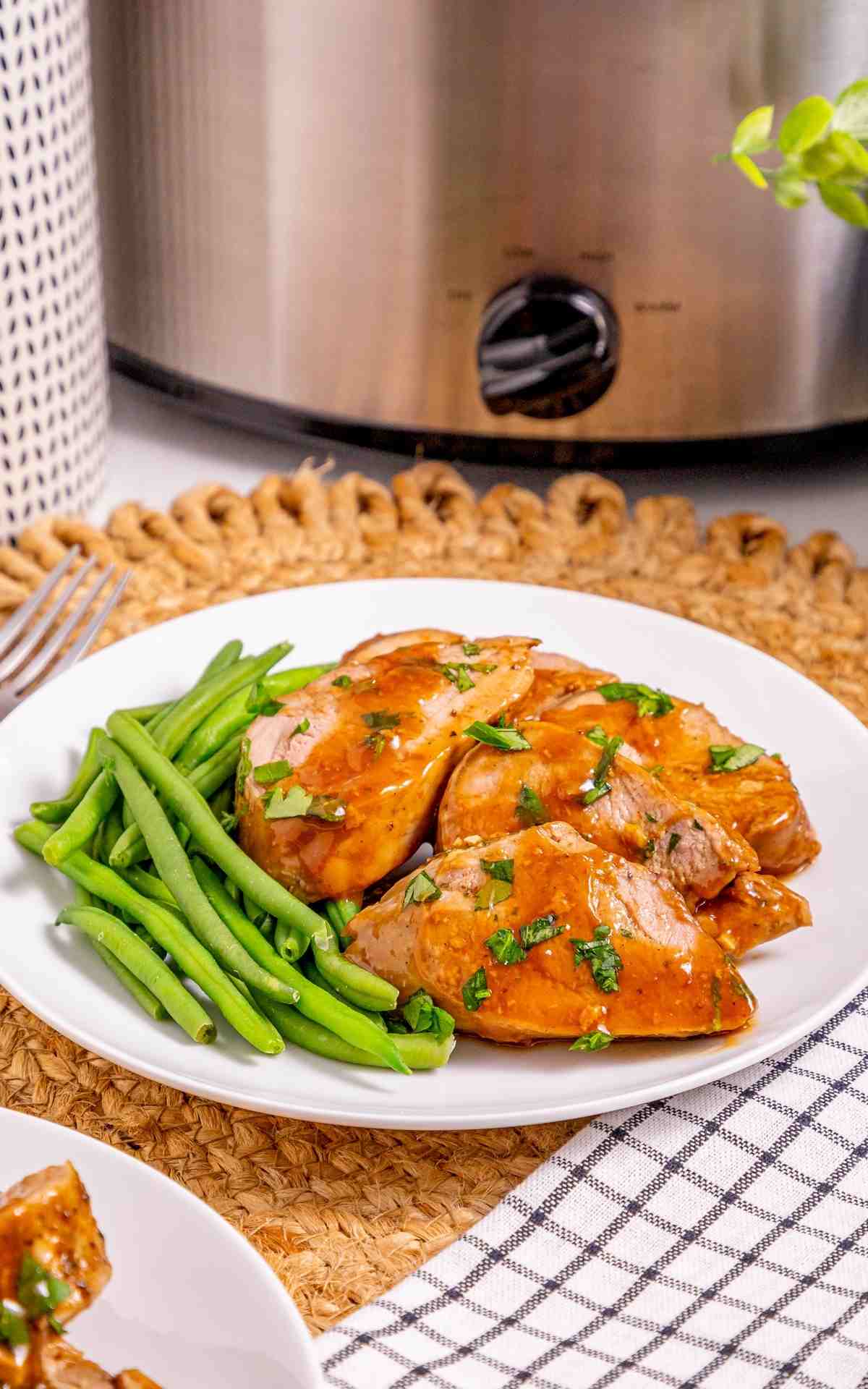 Slow Cooker pork tenderloin slices with green beans on a plate.