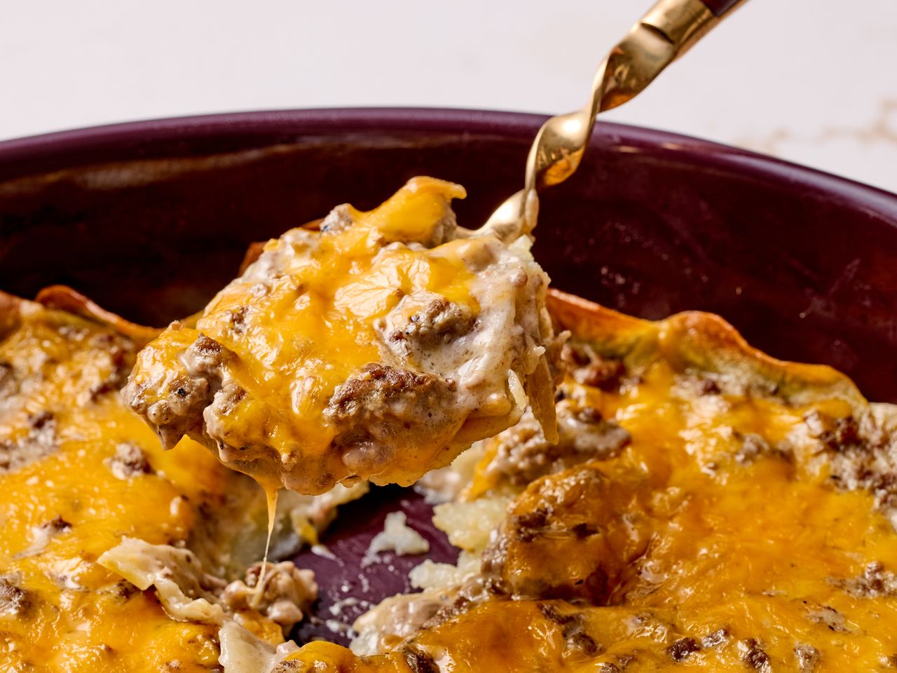 A spoonful of cheesy ground beef and potatoes from a baked dish