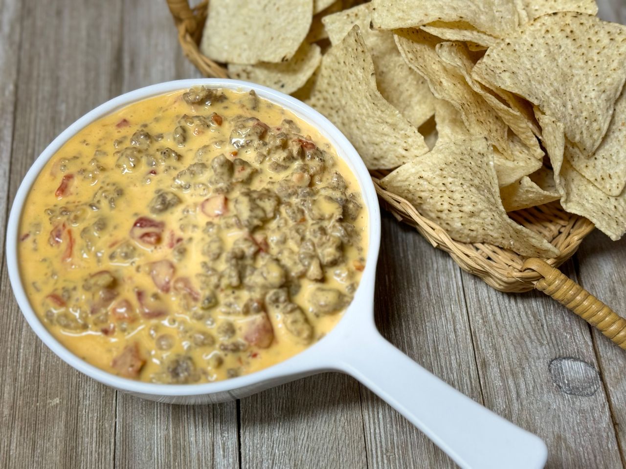 birds eye view of hot cheese dip with sausage and basket of tortilla chips