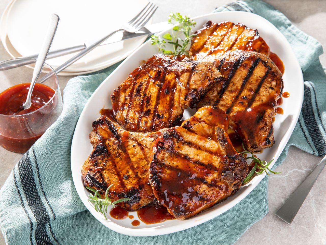 Family style platter of World's Best Honey Garlic Pork Chops garnished with extra sauce and fresh herbs.