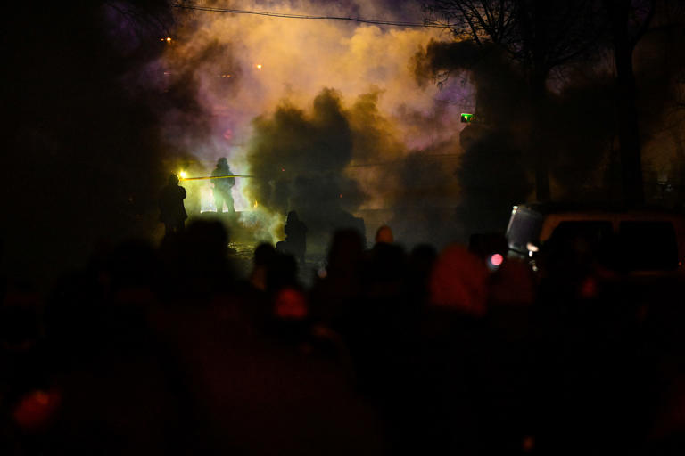 Law enforcement officers clash with protesters at the scene where ICE officers shot a man in the leg on Wednesday in Minneapolis.