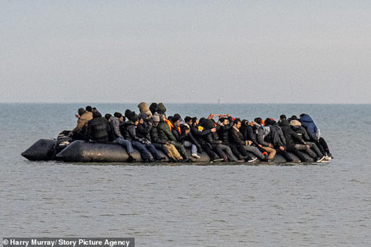 Migrants were pictured today crammed shoulder-to-shoulder on an overloaded inflatable dinghy as they attempted the latest dangerous crossing of the English Channel in freezing winter conditions