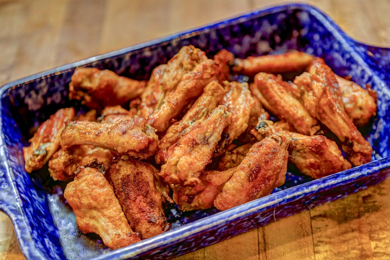 A blue bowl full of seasoned baked wings.