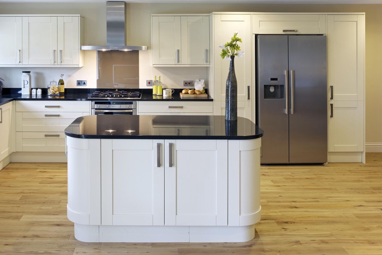 Modern kitchen with white cabinets stainless steel appliances and a central island with a black countertop