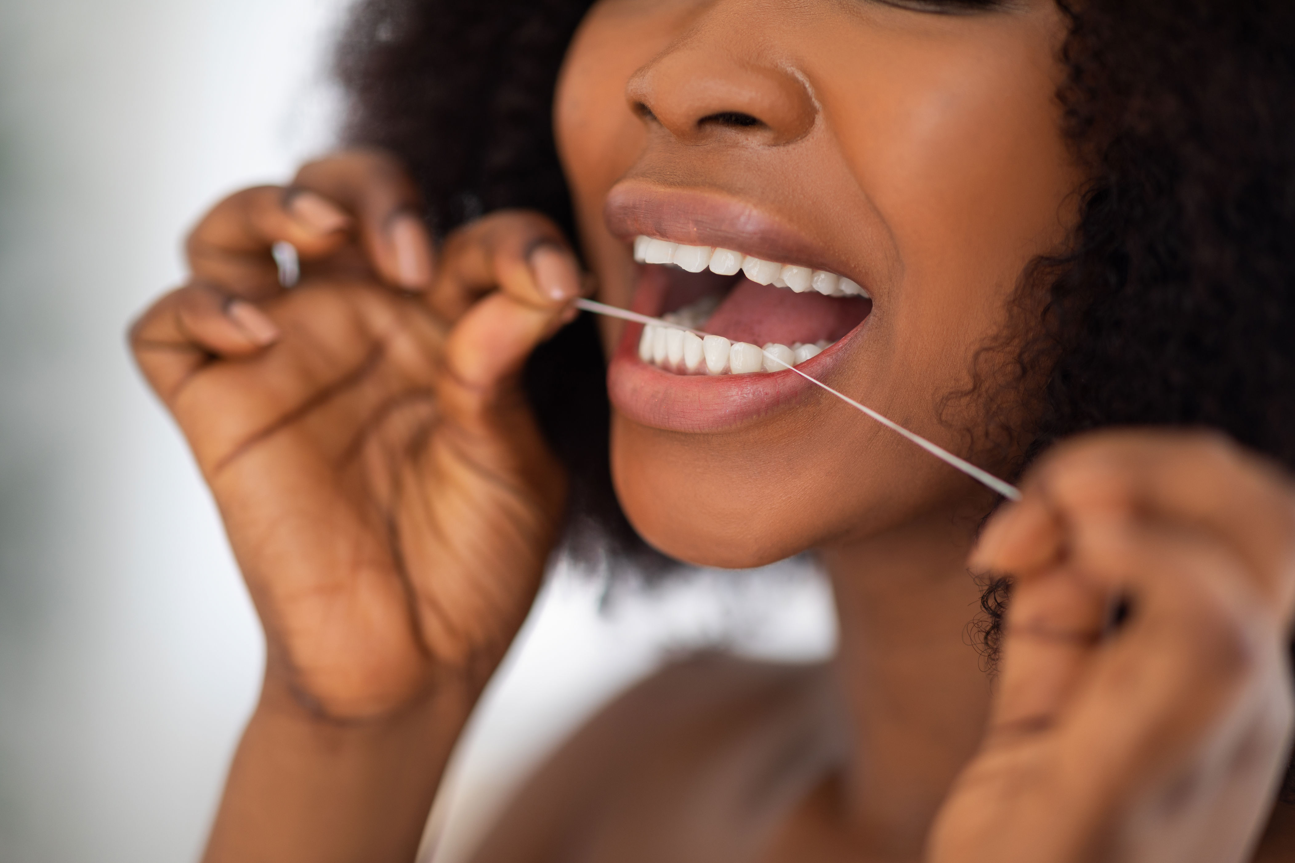 Person flossing teeth, focusing on oral hygiene, highlighting its importance in maintaining a professional appearance in work environments