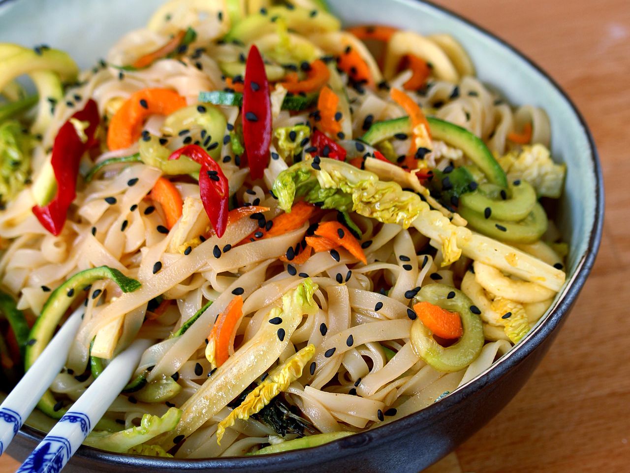 close up view of Thai Rice Noodle Salad garnished with black sesame seeds in a bowl with chopsticks