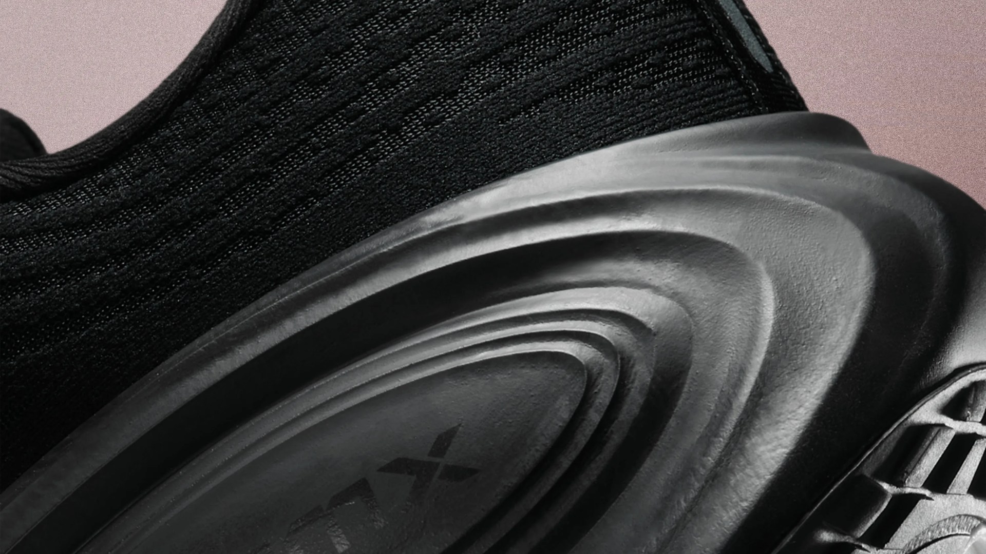 Close-up of a black sneaker midsole with textured, wavy design and knit fabric upper.