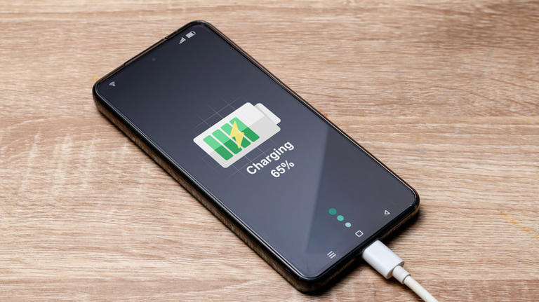 smartphone plugged into a phone charger and sitting on a floor