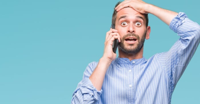 young man holding cellphone to his ear and holding his hand to his forehead like he made a mistake
