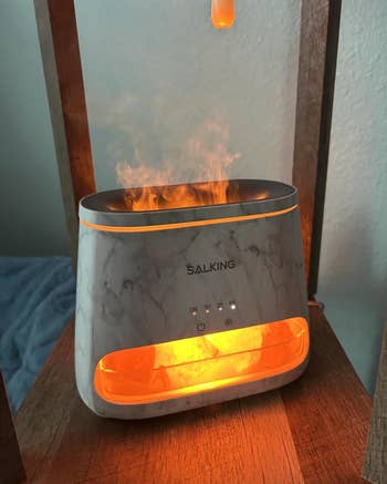 A marble-patterned essential oil diffuser emits a mist and glows. Features include a timer, light, and mist controls