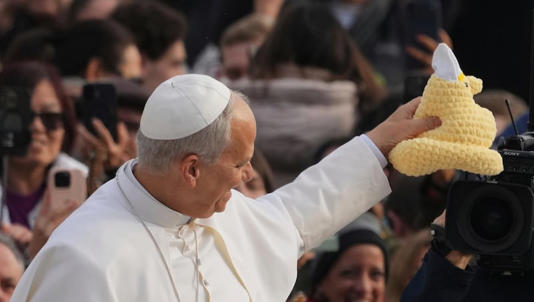 Pope Leo XIV holds an item received by a faithful as he arrives for his weekly general audience in St. Peter's Square at The Vatican, Wednesday, Dec.17, 2025.