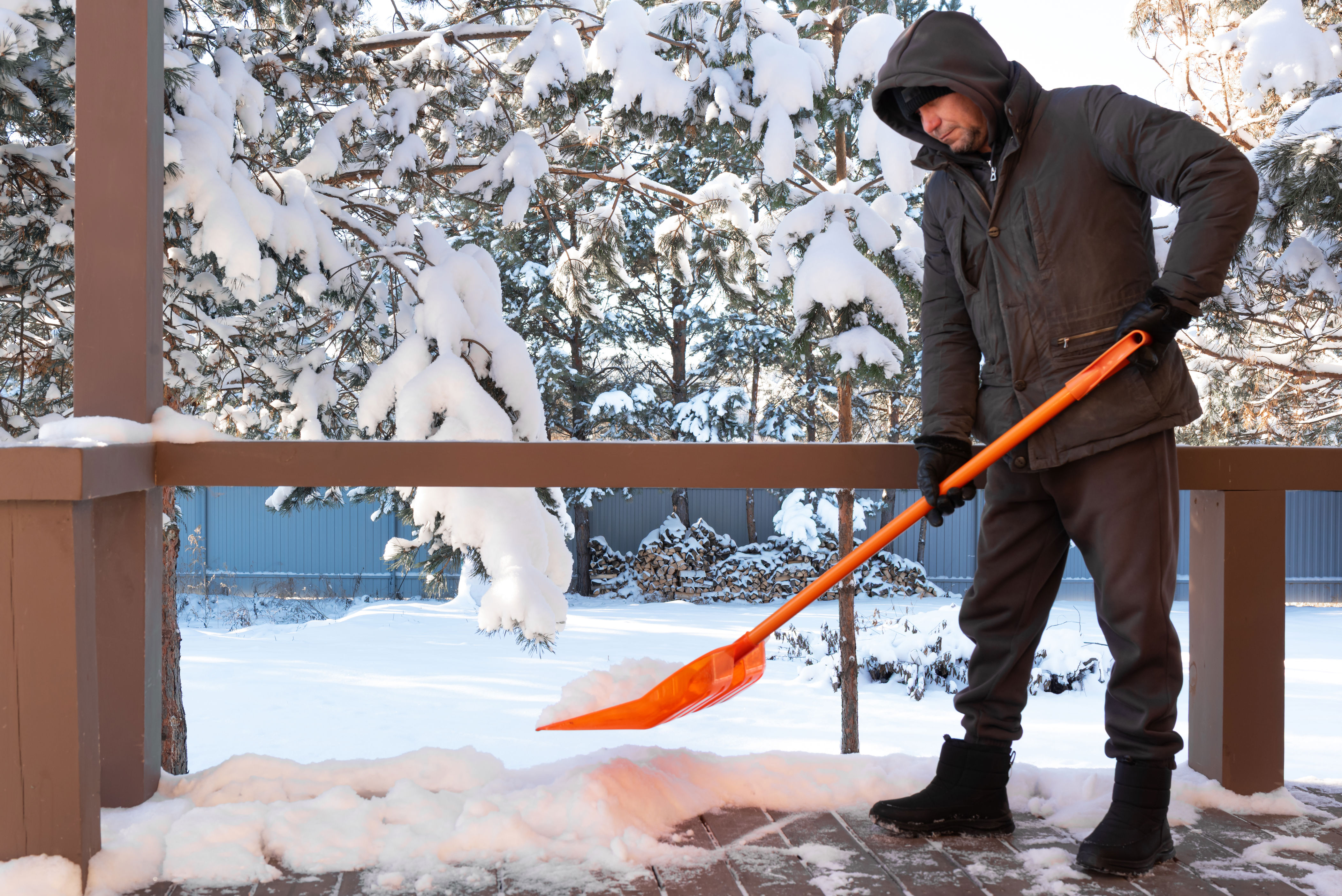 Man removing snow from an outdoor deck.