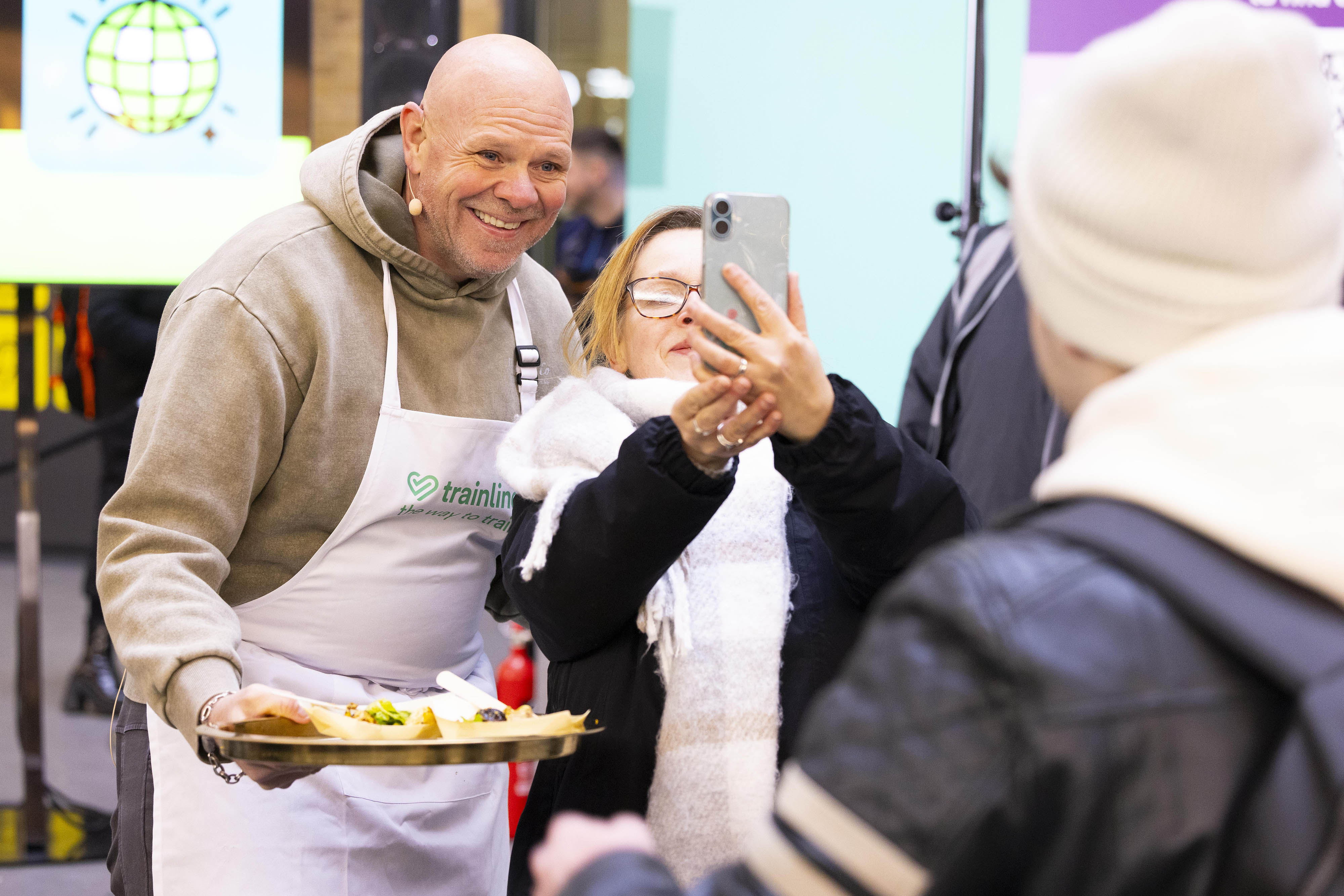 Shot of chef Tom Kerridge taking a picture with a fan while holding a plate of food