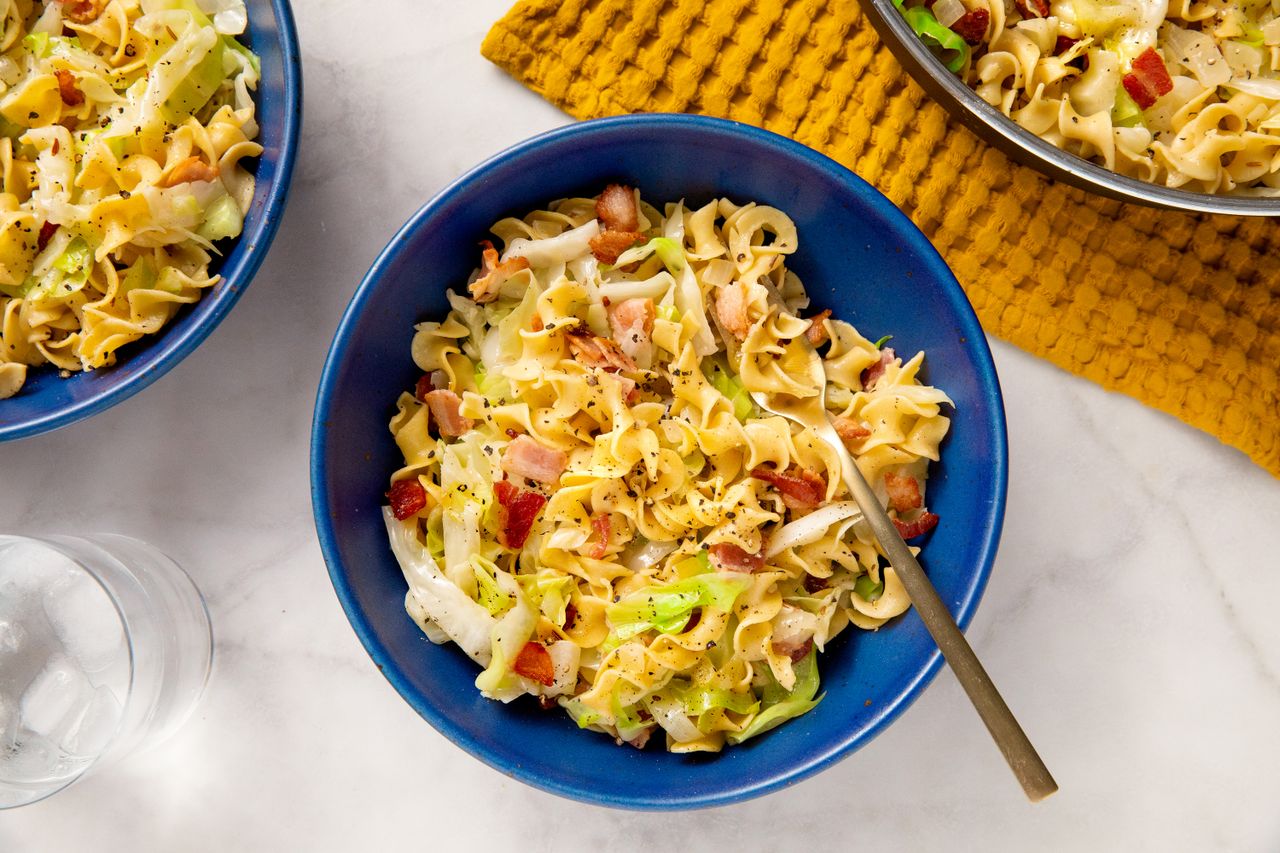 A bowl of haluski a noodle dish with cabbage and bacon served on a table with a yellow cloth