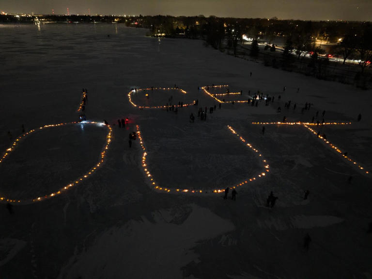The words ICE OUT lit up in candles on a frozen lake