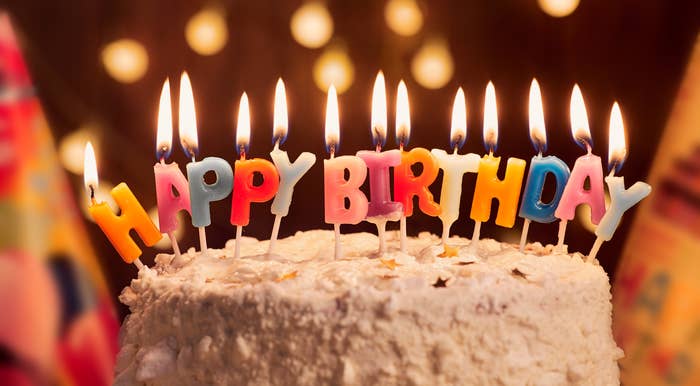 Birthday cake with lit candles spelling "Happy Birthday" on top