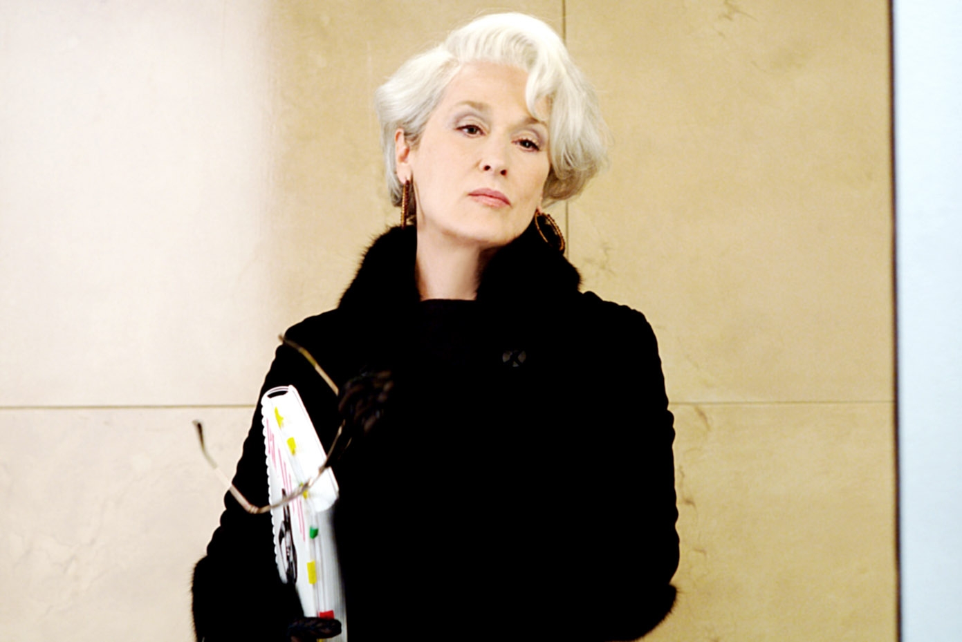 A person in elegant coat, looking composed against a neutral background