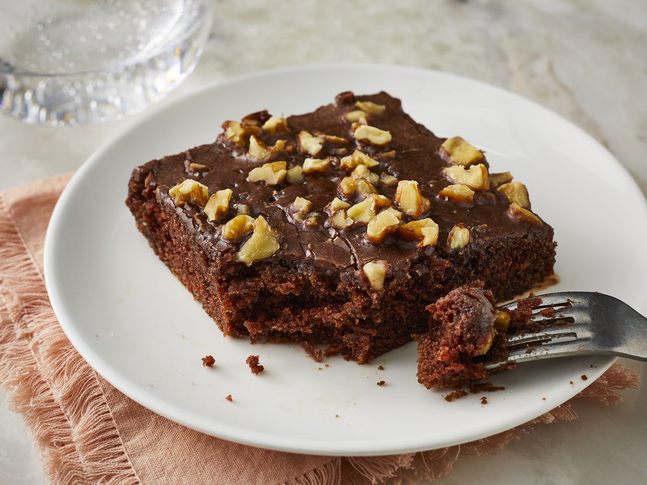 mid angle looking at a slice of chocolate Texas sheet cake, with a piece taken off by a fork