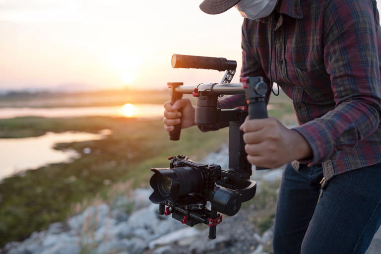 A videographer filming a landscape. sutiporn somnam/Getty Images