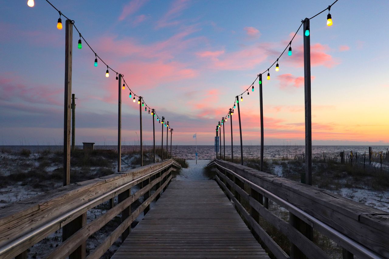 A pier leading to a beach at sunset