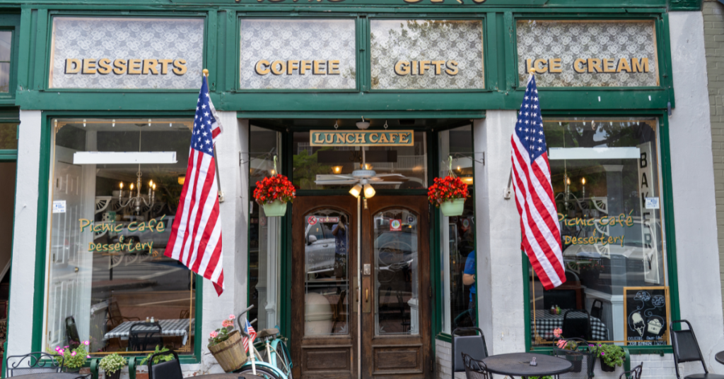 Front of an old-fashioned cafe with wide, wooden double doors flanked by two American flags