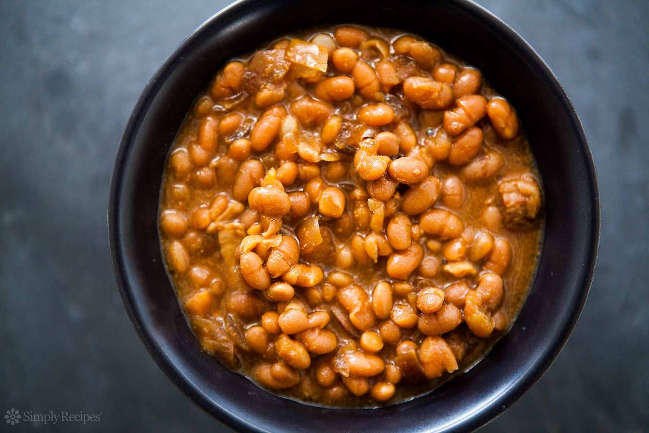A black bowl of baked beans viewed from above.