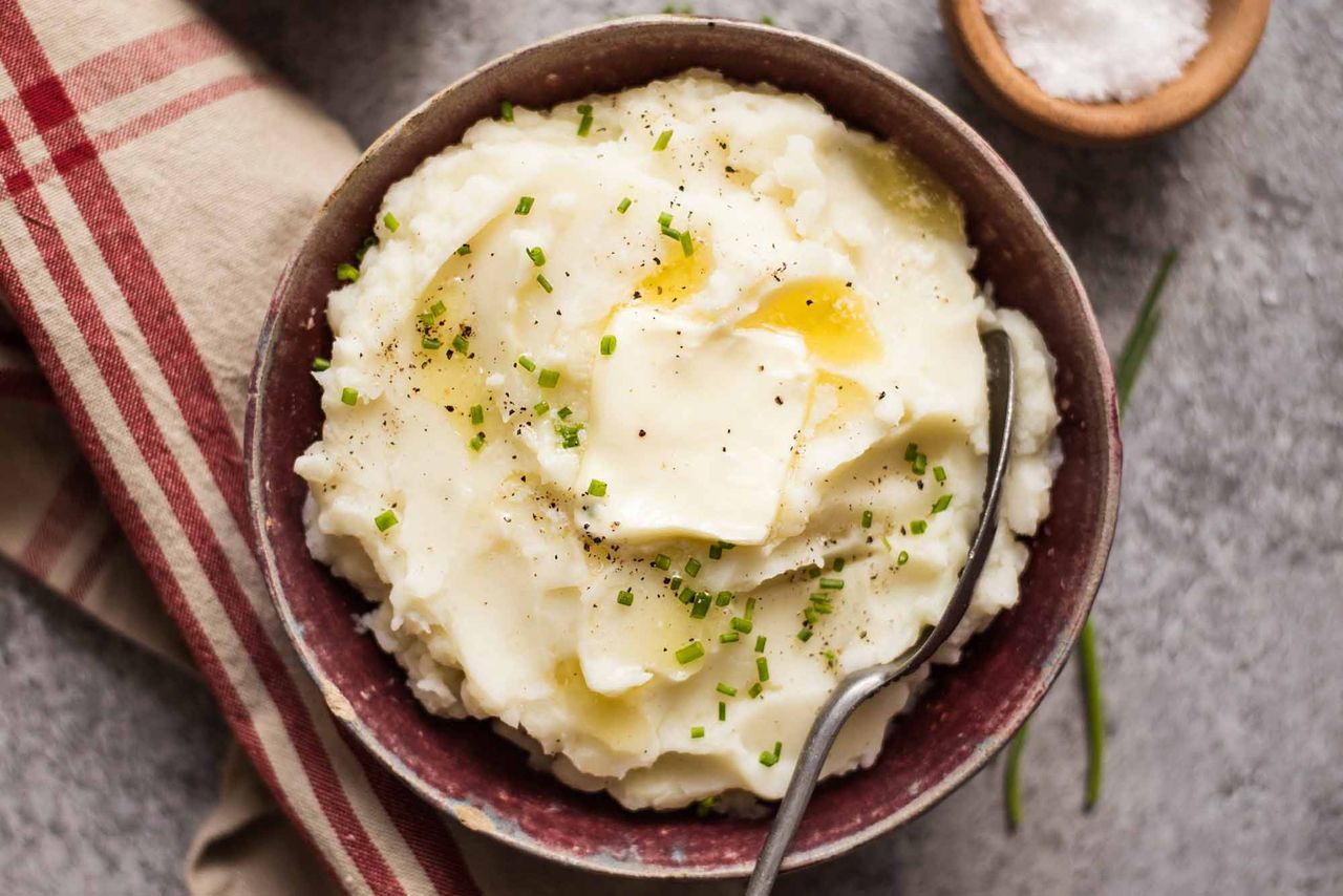 slow cooker mashed potatoes in a bowl with a pat of butter