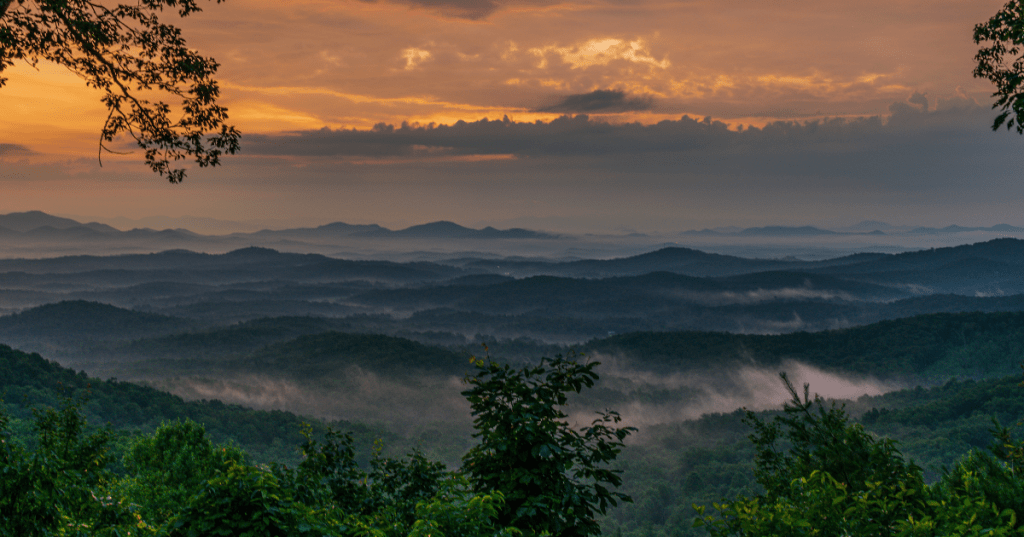 Hazy blue-grey mountains with fog drifting over them at sunrise
