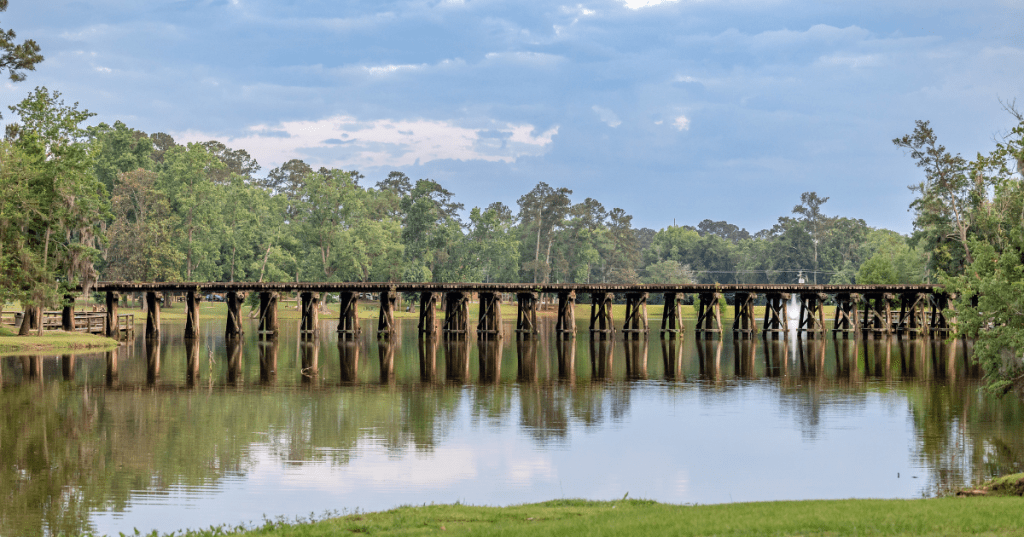 A wooden railroad bridge crossing a small body of water under blue skies