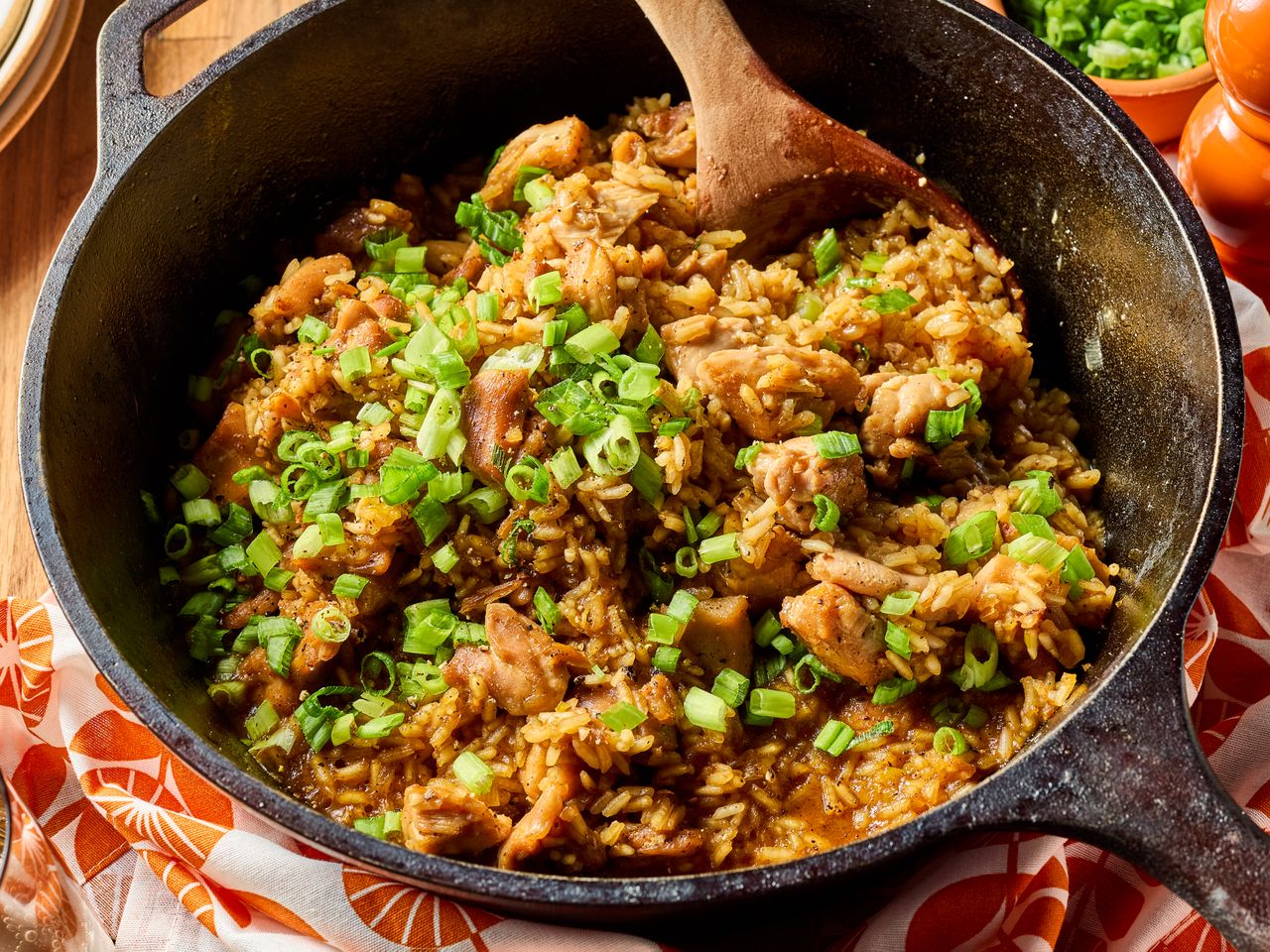 A cooked dish consisting of chicken rice and garnished green onions served in a black pot