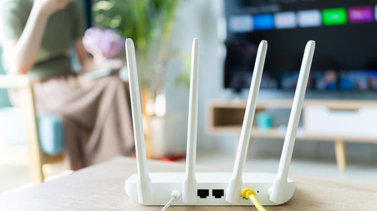 A router on a table in front of a TV.