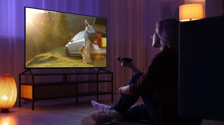 A person sitting watching TV in a dimmed room