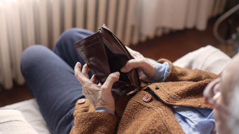 An older woman looking through an empty purse