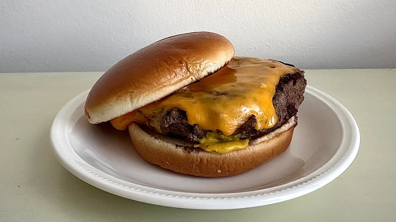 Texas Roadhouse's cheeseburger on a small white plate in front of a neutral background