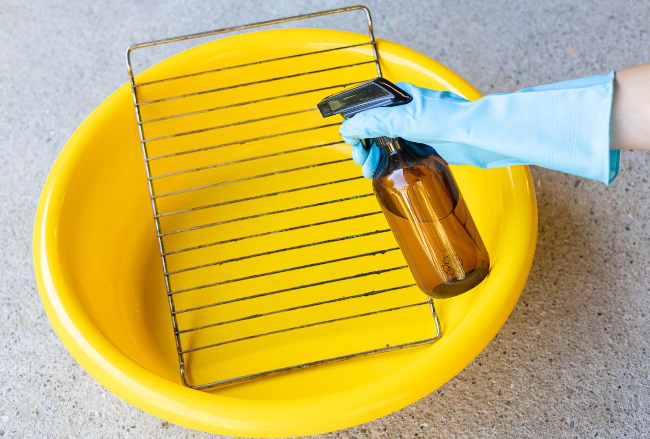 Placing the oven rack in a plastic tub before spraying with cleaner